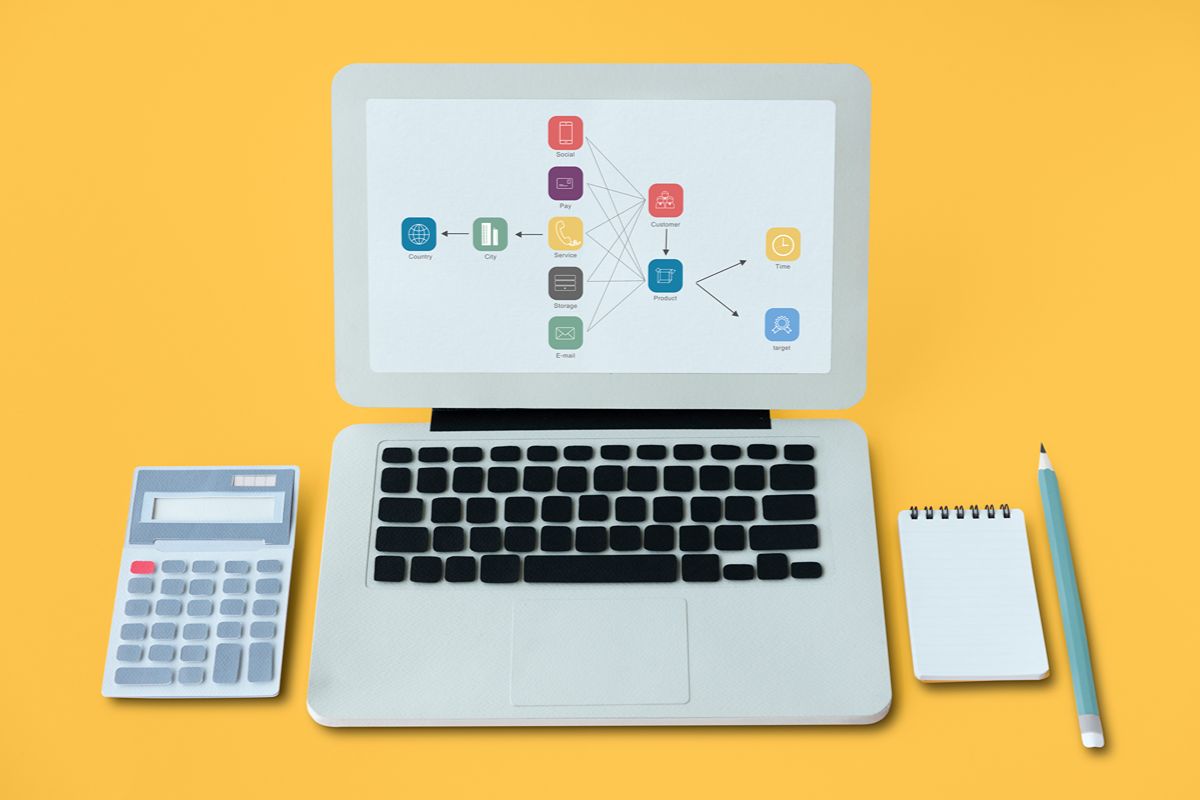 Laptop with connected business system icons, calculator, and notebook representing computerized accounting and ERP workflow management