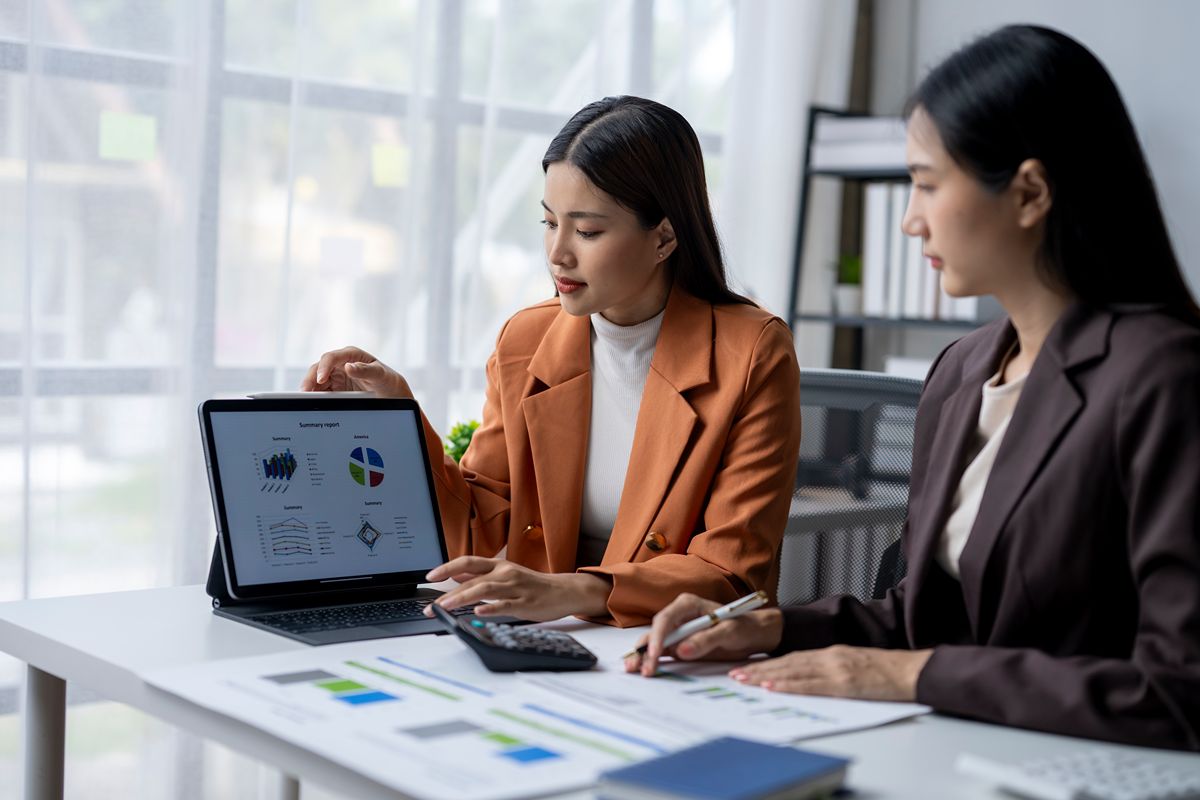 Two finance professionals reviewing accounting reports and charts displayed on a tablet
