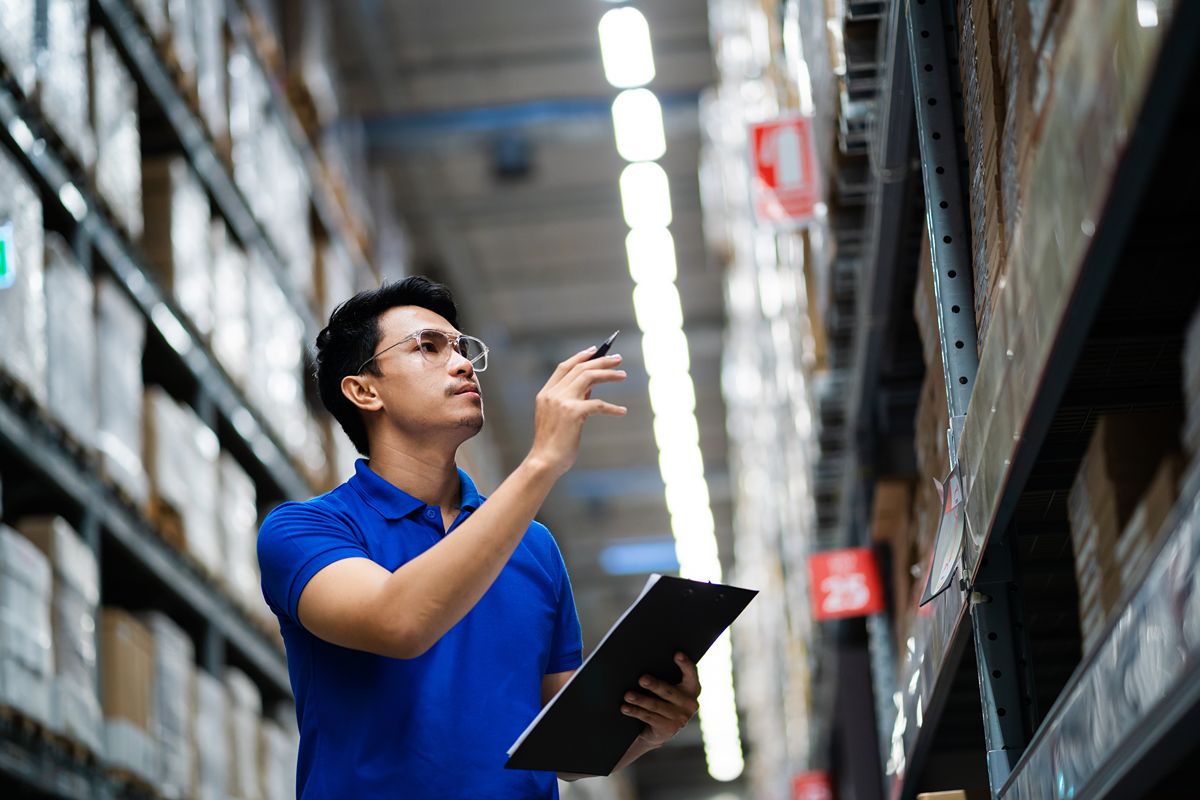 Warehouse employee checking stock levels during a cycle count with a clipboard