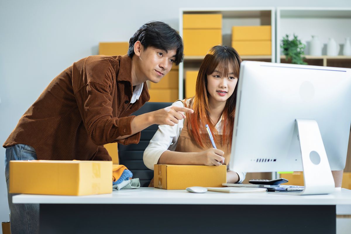Two employees reviewing inventory records on a computer beside packaged goods