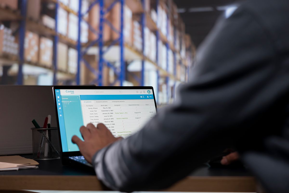 Warehouse professional reviewing inventory data on a laptop to forecast demand and improve stock planning