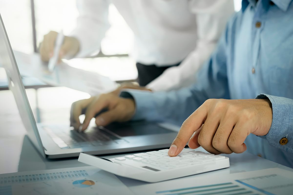 employee reviewing accounting documents and invoice data using a laptop and calculator